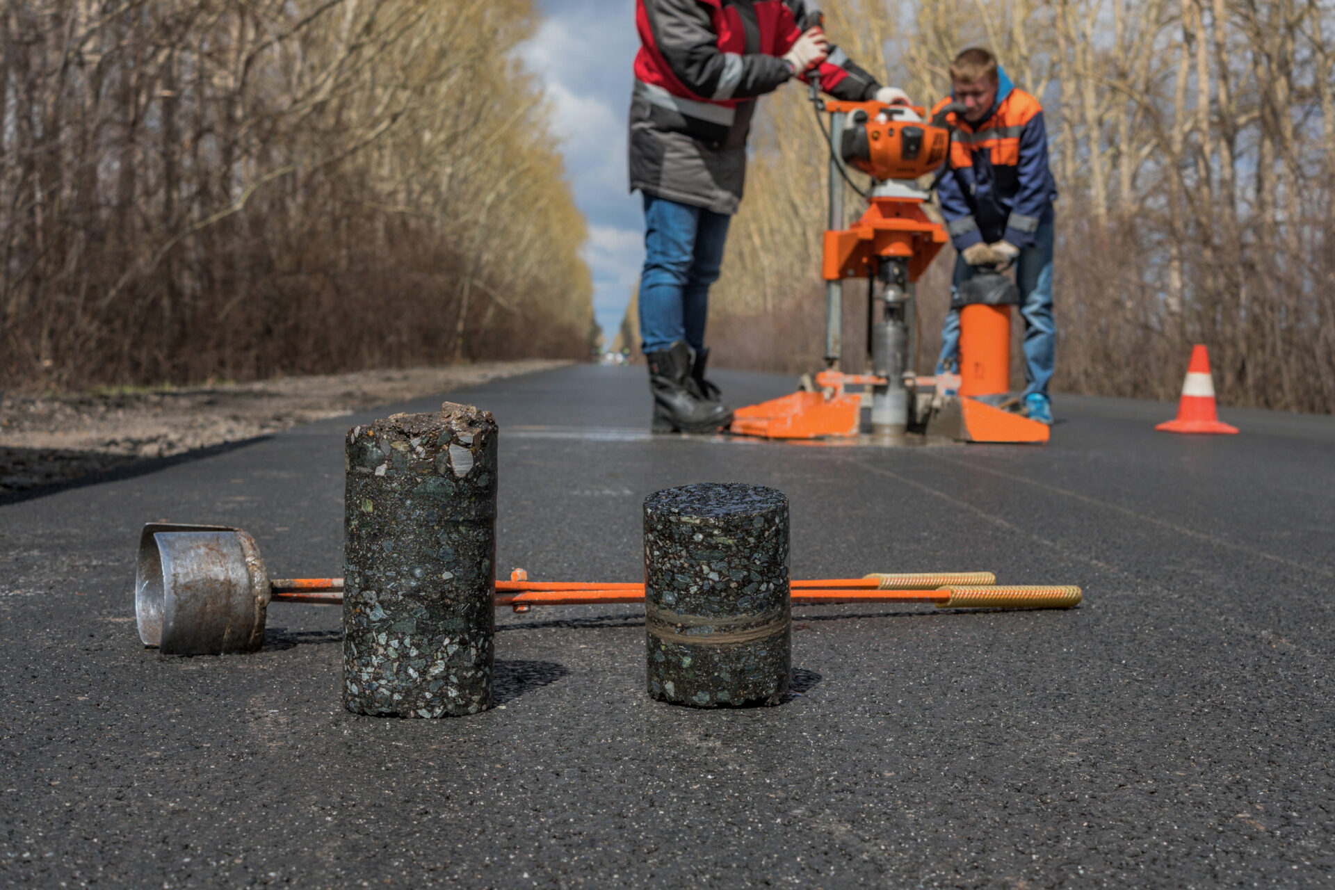 Worker cut by the core sampler samples of asphalt concrete on the road. Asphalt concrete cores close-up