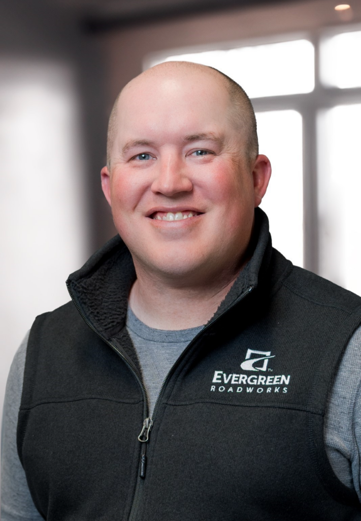 Man smiles at the camera, wearing an Evergreen Roadworks vest