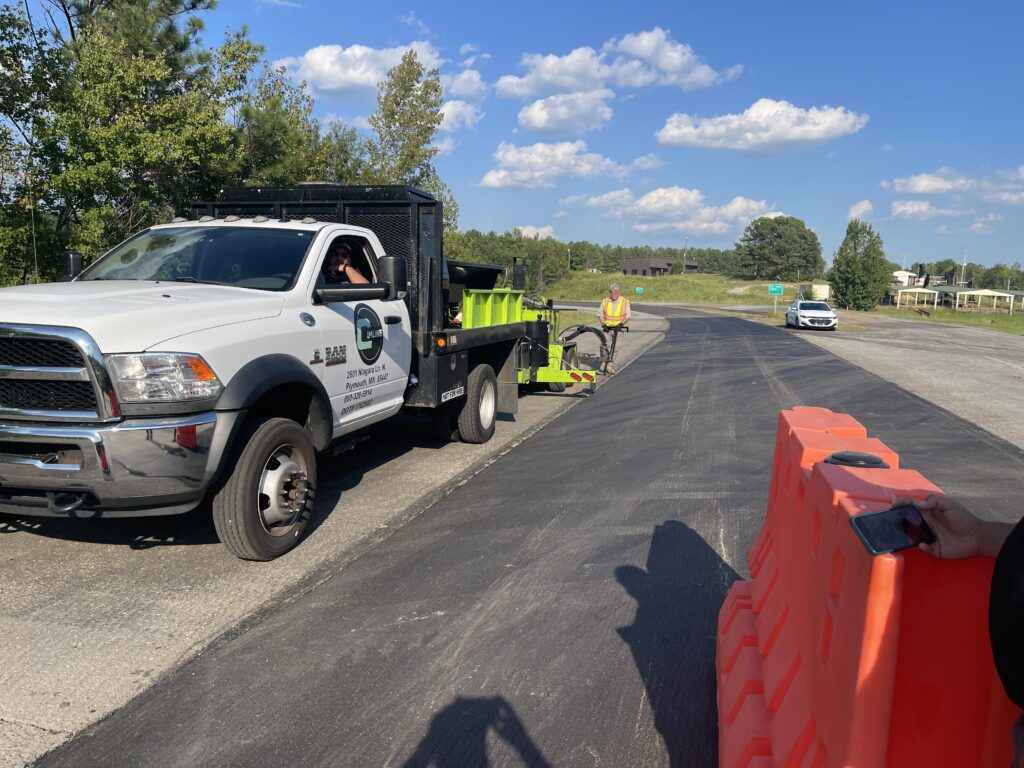 VRAM being sprayed on the road by a man directing the sprayer