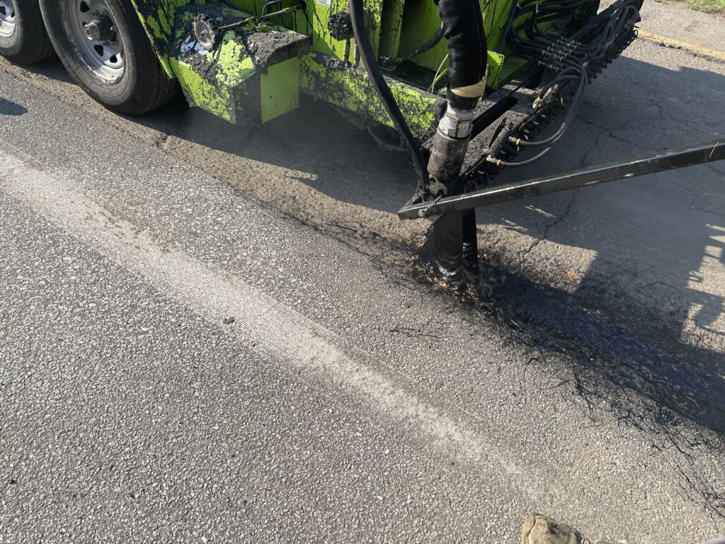 close up of an asphalt emulsion being sprayed on a road